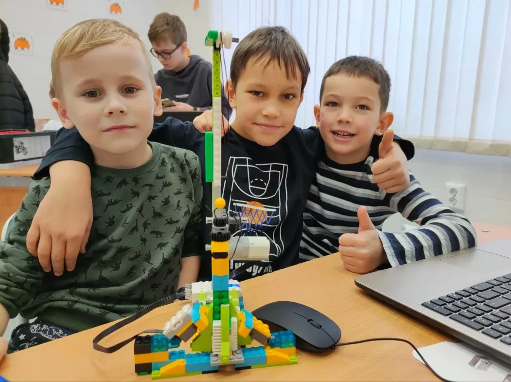 Трое мальчиков с моделью лифта из LEGO в Лига Роботов